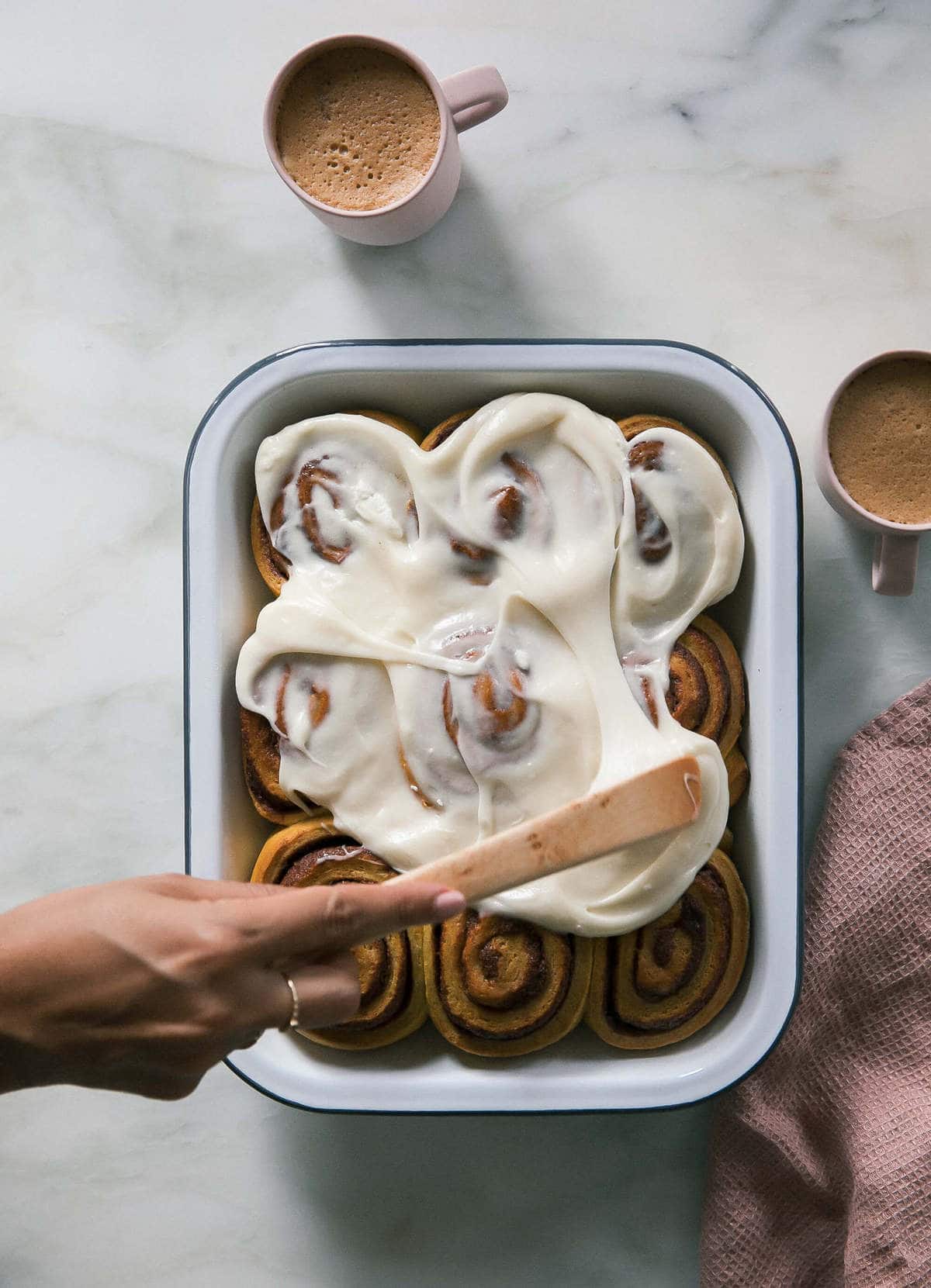 Frosting being smothered on pumpkin cinnamon rolls. 